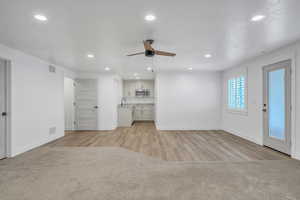 Unfurnished living room featuring ceiling fan, sink, and light hardwood / wood-style flooring