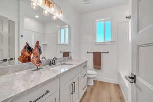 Full bathroom featuring hardwood / wood-style flooring, toilet, vanity, and a wealth of natural light