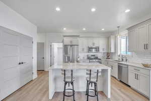 Kitchen with a kitchen island, hanging light fixtures, light wood-type flooring, and appliances with stainless steel finishes