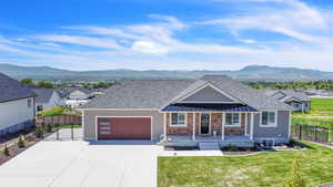 Ranch-style home with a garage, a mountain view, and a front lawn