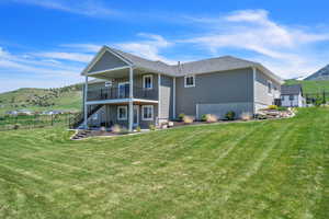 Rear view of house featuring a yard, a mountain view, and a balcony