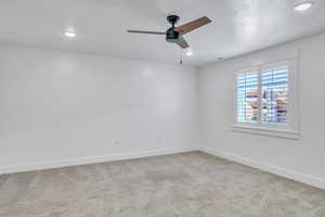 Carpeted empty room with ceiling fan and a textured ceiling