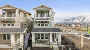 Model home - View of front of house with stone siding, a residential view, a mountain view, covered porch, and a shingled roof