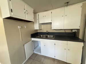 Kitchen with sink, white cabinets, and light tile patterned floors