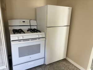 Kitchen featuring dark tile patterned floors and white appliances