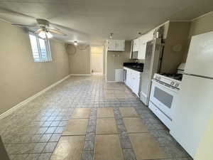 Kitchen with ceiling fan, sink, tile patterned flooring, white appliances, and white cabinets