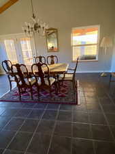 Tiled dining room featuring plenty of natural light, high vaulted ceiling, and a notable chandelier