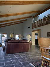 Living room featuring an inviting chandelier, high vaulted ceiling, beamed ceiling, and dark tile patterned floors