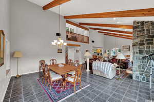 Tiled dining room with high vaulted ceiling, beam ceiling, and an inviting chandelier