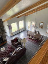 Living room with french doors, a textured ceiling, brick wall, dark tile patterned flooring, and a stone fireplace