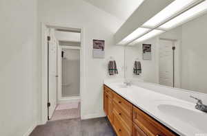 Bathroom featuring a shower with shower door and double sink vanity