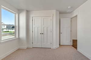 Unfurnished bedroom featuring light carpet and a closet