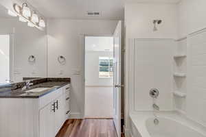 Bathroom with wood-type flooring, shower / tub combination, and vanity