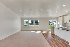 Kitchen featuring hardwood / wood-style floors, white cabinetry, sink, and a wealth of natural light