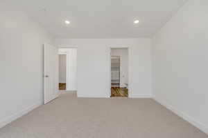 Unfurnished bedroom featuring light colored carpet, a closet, and a spacious closet