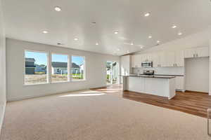 Kitchen featuring light hardwood / wood-style floors, sink, white cabinets, lofted ceiling, and stainless steel appliances