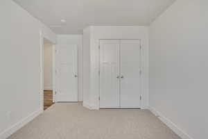 Unfurnished bedroom featuring a closet and light colored carpet