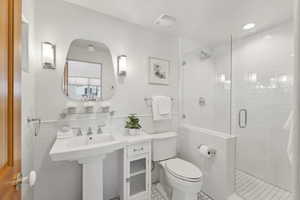 Bathroom featuring a shower with door, tile walls, toilet, and tile patterned flooring