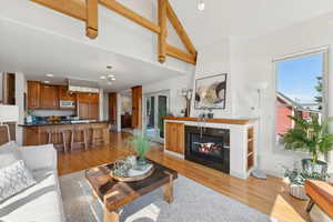 Living room with vaulted ceiling, a fireplace, an inviting chandelier, and light hardwood / wood-style flooring