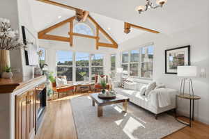 Living room with lofted ceiling with beams, a chandelier, and light hardwood / wood-style floors