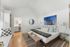 Bedroom with high vaulted ceiling, connected bathroom, and light hardwood / wood-style flooring