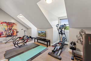 Workout room with vaulted ceiling and carpet floors