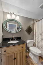 Bathroom featuring vanity with extensive cabinet space, toilet, and tile floors