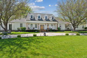 Cape cod house featuring a porch and a front lawn