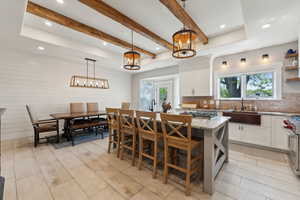 Kitchen with light stone counters, a center island, sink, a breakfast bar area, and white cabinetry