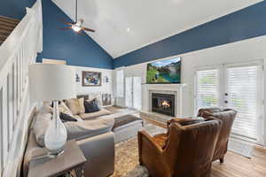 Living room with ceiling fan, french doors, a fireplace, wood-type flooring, and high vaulted ceiling