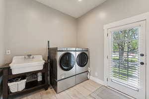 Laundry area featuring sink, light wood-type flooring, and washing machine and clothes dryer