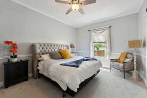 Carpeted bedroom featuring ceiling fan and crown molding