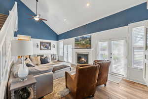 Living room featuring french doors, light hardwood / wood-style flooring, a tile fireplace, high vaulted ceiling, and ceiling fan