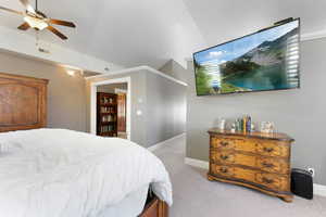 Carpeted bedroom featuring ceiling fan and lofted ceiling