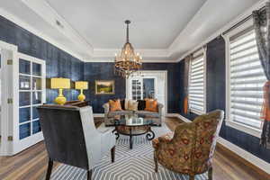 Living room with a tray ceiling, hardwood / wood-style flooring, and a chandelier