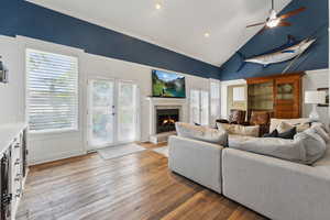 Living room featuring light hardwood / wood-style floors, a tile fireplace, ceiling fan, and vaulted ceiling