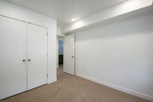 Unfurnished bedroom with a closet and light carpet