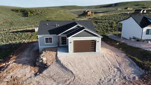 View of front of home with a garage, a rural view, and driveway