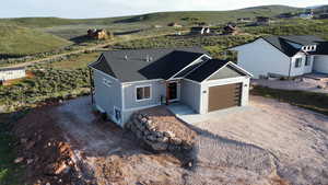 View of front of home with a garage, a mountain view, a shingled roof, and dirt driveway