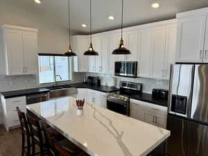 Kitchen featuring white cabinets, stainless steel appliances, a sink, and a center island