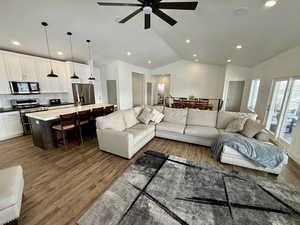 Living area featuring lofted ceiling, wood finished floors, a ceiling fan, and recessed lighting