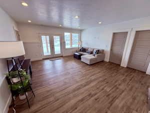 Living room with baseboards, wood finished floors, a textured ceiling, french doors, and recessed lighting