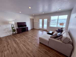 Living room featuring baseboards, wood finished floors, a textured ceiling, french doors, and recessed lighting