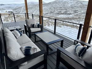 Snow covered deck with a mountain view and outdoor lounge area