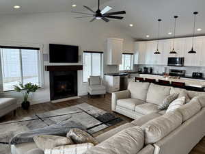 Living room featuring dark wood finished floors, a ceiling fan, a fireplace, high vaulted ceiling, and recessed lighting