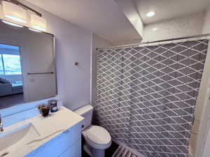 Bathroom featuring toilet, vanity, and a shower with shower curtain