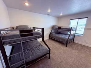 Bedroom with visible vents, a textured ceiling, baseboards, and carpet flooring