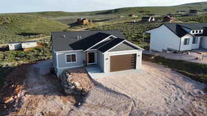 View of front facade with a shingled roof, an attached garage, and dirt driveway