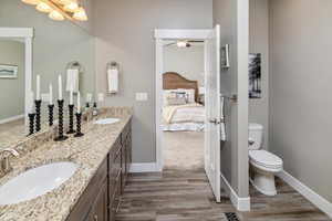 Bathroom with ceiling fan, double vanity, toilet, and wood-type flooring