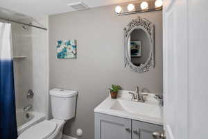 Full bathroom with shower / tub combo with curtain, oversized vanity, and toilet